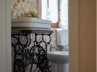 Bagno privato del B&B Josephine con lavabo su base di macchina da cucire d'epoca e piastrelle floreali